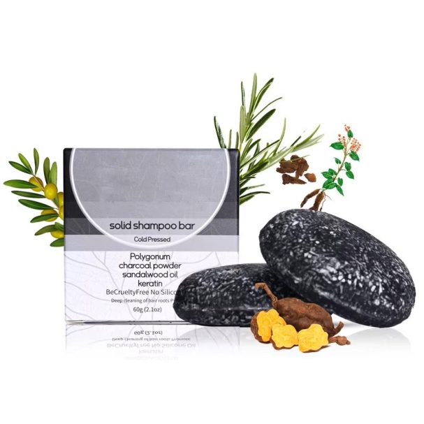 Zwarte shampoo bar met natuurlijke ingrediënten en een doosje ernaast.